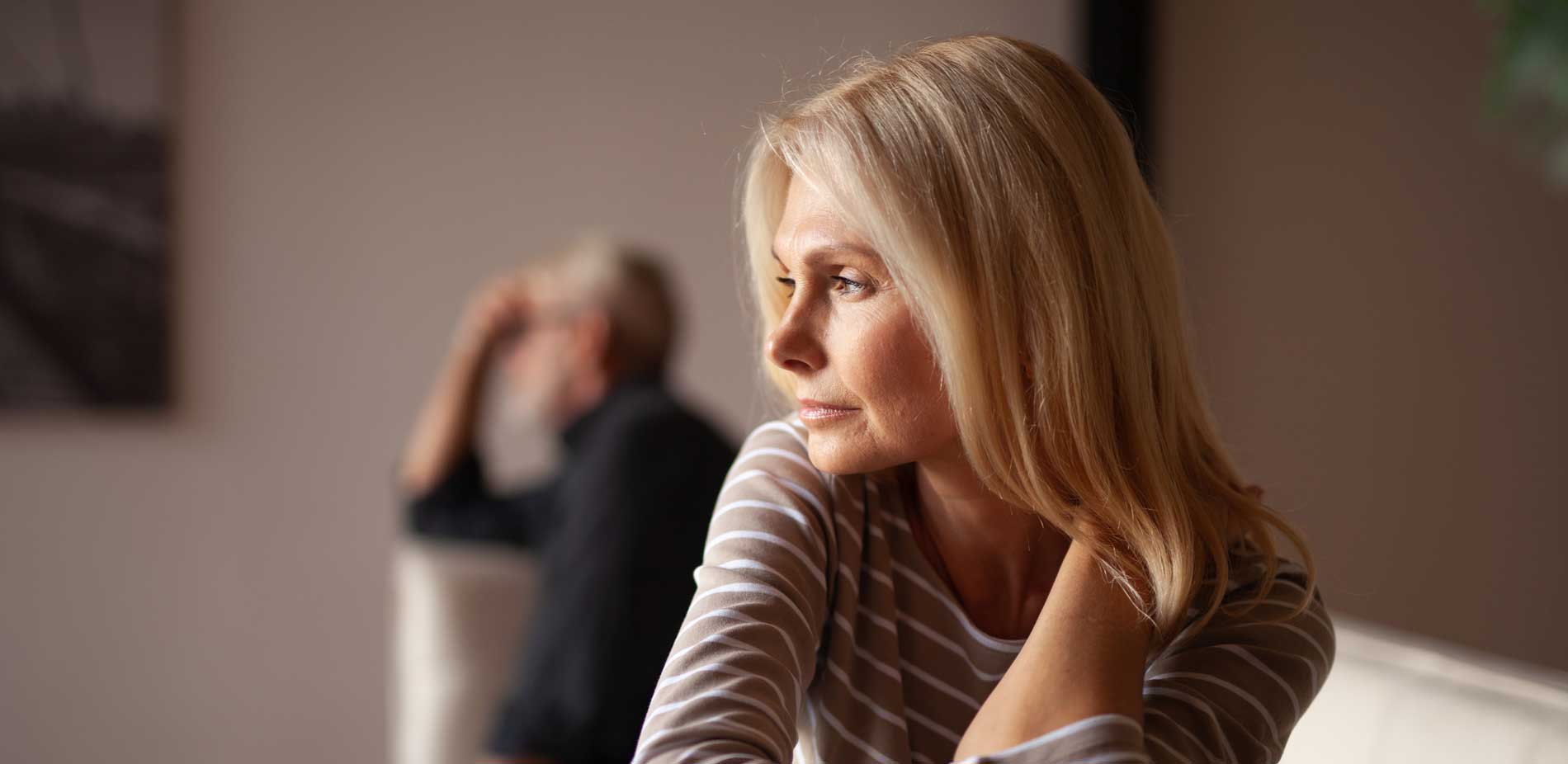 Frau ist traurig, Mann im Hintergrund - Alles rund ums Thema Scheidung