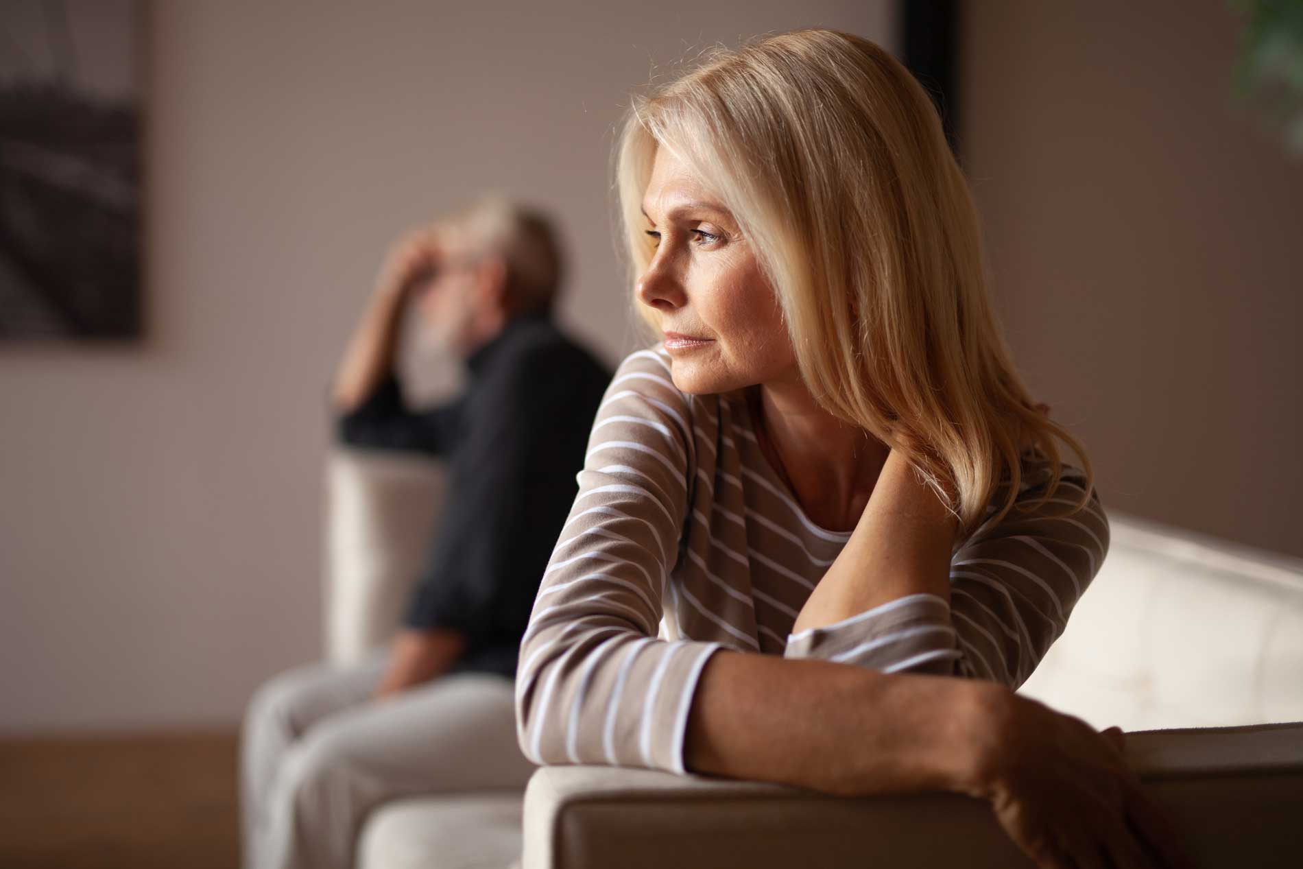 Couple âgé assis sur le sofa, réfléchissant